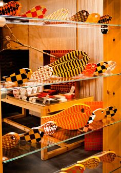 several wooden fish on display in a glass case with yellow and black checkerboard