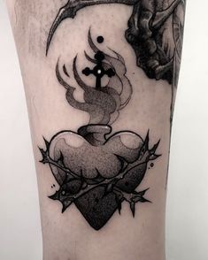 a black and white tattoo on the leg of a person with a bird, cross, and heart