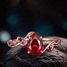 a close up of a ring with a red stone on it's center and two pink stones in the middle