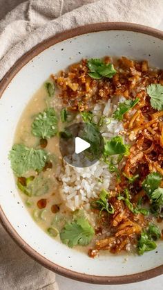 a bowl filled with rice, meat and cilantro on top of a table