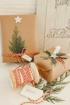 two wrapped presents sitting next to each other on top of a white table with red and green twine