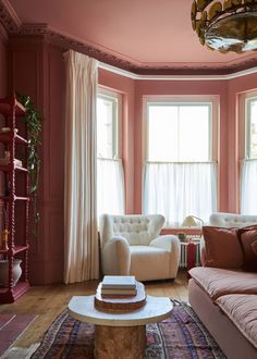 a living room filled with furniture and pink walls