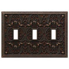 an ornate cast iron outlet cover with two toggles and decorative designs on the front