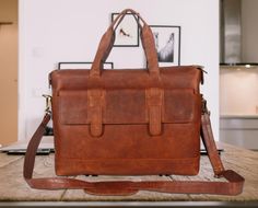 a brown leather briefcase sitting on top of a wooden table