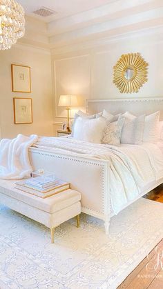 a white bed sitting in a bedroom next to a chandelier above a window