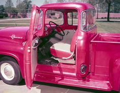 an old red truck parked in a parking lot