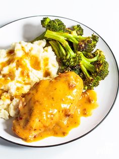 a white plate topped with chicken, mashed potatoes and broccoli covered in gravy