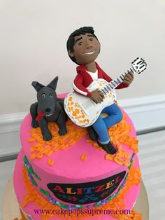 a birthday cake with a man playing the guitar and dog figurine on top