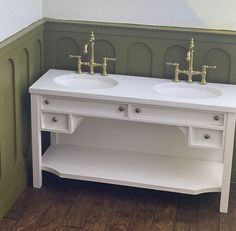 two white sinks sitting next to each other in a room with green walls and wood flooring