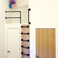 a white room with a wooden door and some black bars on the wall next to it