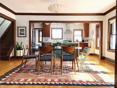 a dining room and kitchen area with hardwood floors, windows, and rugs on the floor