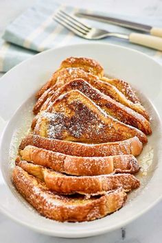 french toast on a white plate with powdered sugar in the middle and text overlay that reads how to make french toast