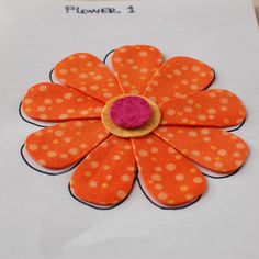 an orange flower with white dots on it and a needle in the center is being used to sew