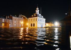 a flooded street at night with buildings in the background