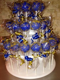 blue and gold candy lollipops are arranged on a cake stand