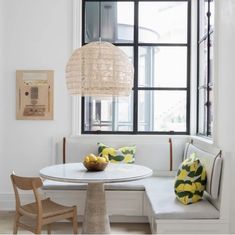 a table with some fruit on it in front of a window and a white bench