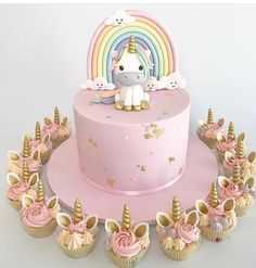 a pink unicorn cake with cupcakes on it and an instagramr above