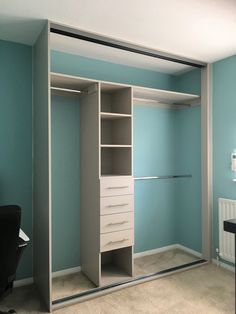 an empty closet with blue walls and white drawers