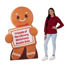 a woman standing next to a cardboard christmas cookie sale sign with a smiling ginger on it