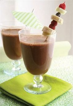 two glasses filled with hot chocolate and marshmallows on top of a green napkin