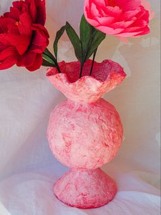 two red flowers are in a pink vase