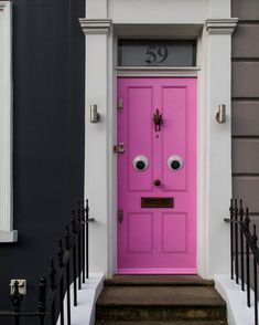 a bright pink door with googly eyes on it's front entrance to a house