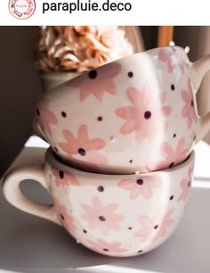 two coffee cups are stacked on top of each other with pink flowers painted on them