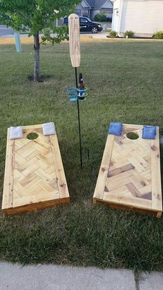 two cornhole boards sitting in the grass next to a tree with an arrow on it