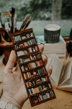 a person holding up a book in front of an open book shelf filled with books