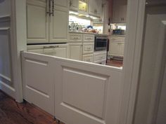 an open kitchen with white cabinets and wood flooring, viewed from the doorway to the dining room