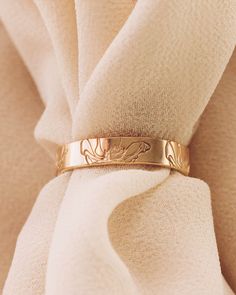 a gold wedding band on top of a white cloth draped in the wind with an image of a dog