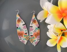 two pairs of beaded earrings next to a flower