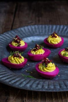 small deviled eggs with mustard and dill on a blue plate sitting on a wooden table