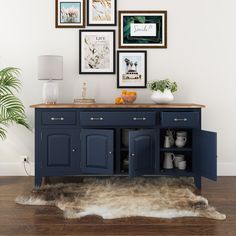 a blue cabinet with pictures on the wall above it and a cowhide rug in front of it