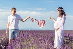 a pregnant woman and man holding clothes in a lavender field