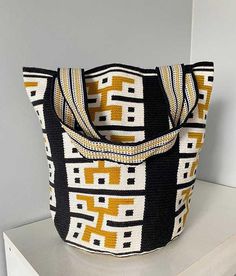 a black and yellow bag sitting on top of a white shelf