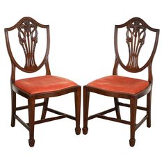 a pair of wooden chairs with red upholstered seat cushions on each side and back