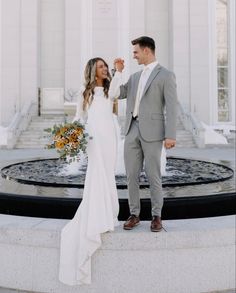 a bride and groom standing in front of a fountain