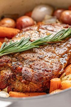 a pot roast with carrots, potatoes and rosemary garnish on the side