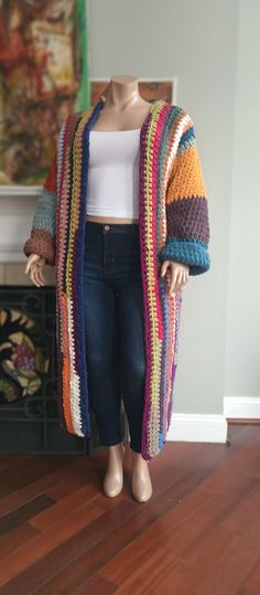 a mannequin wearing a multicolored knitted cardigan standing on a hard wood floor