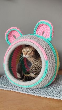 a cat sitting in a crocheted kitty bed