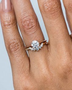 a woman's hand with a diamond ring on top of her finger and an engagement band