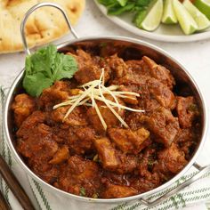 a bowl filled with meat and garnished with parsley next to crackers