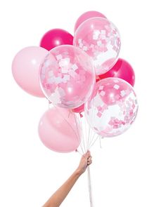 the pink party balloons are being held by a woman's hand, and in front of a box