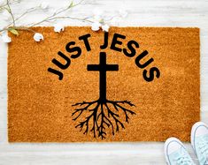 a door mat with the words just jesus and a cross on it next to a pair of shoes