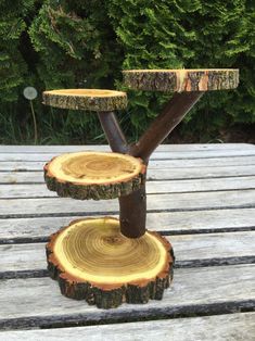 three tiered tree slice stand on top of a wooden table with trees in the background