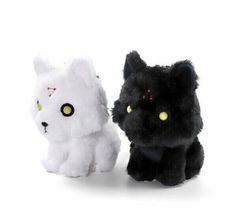 two black and white stuffed animals sitting next to each other on a white surface with yellow eyes