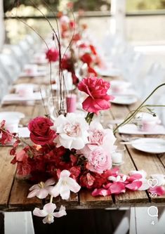 a long table with flowers and plates on it