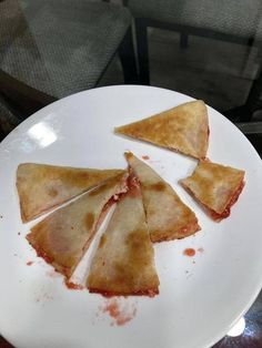 three pieces of pizza on a white plate with red stuff all over the placemat