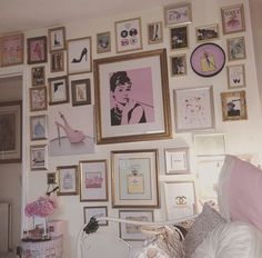 a bedroom with many framed pictures on the wall